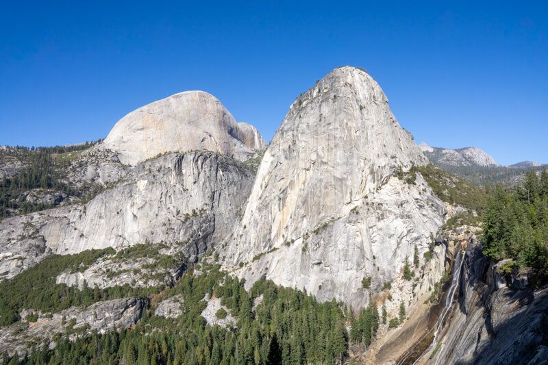 Photo of giant granite domes in a mountain range on a clear day with blue sky in California