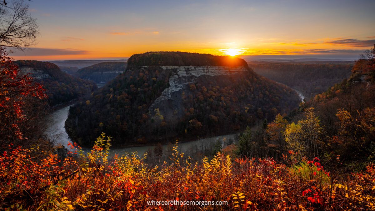 Photo of fall foliage vegetation with a U-shaped river bend and a huge mound in the center at sunrise