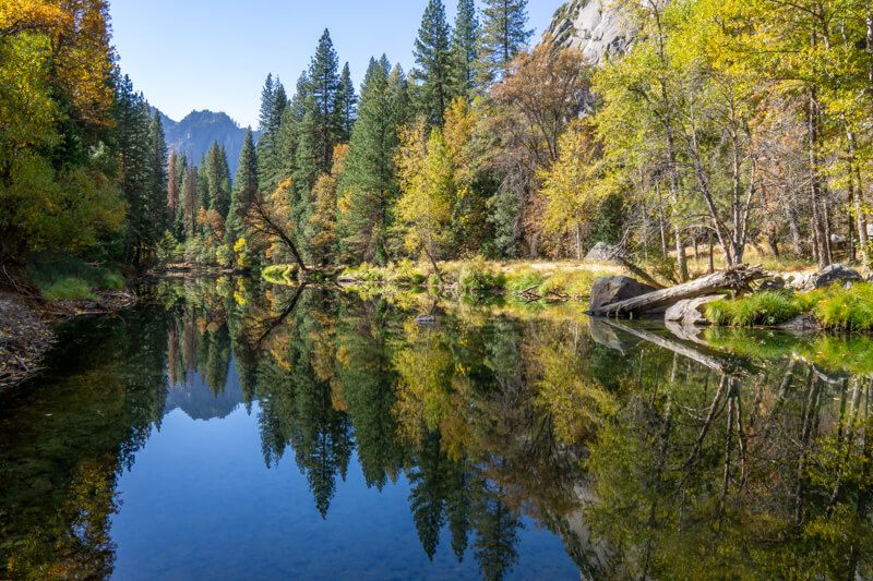 Photo of colorful tree leaves reflecting a perfectly still river