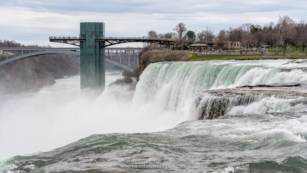 Photo of powerful waterfalls with steam and a viewing platform on a cloudy day