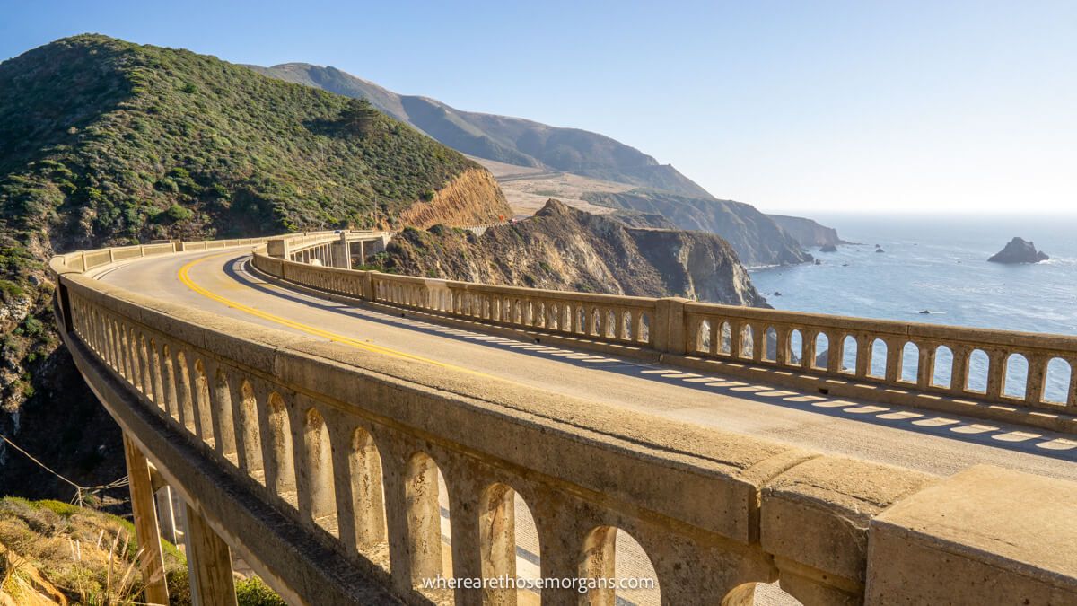 Photo of a curving stone bridge leading to a headland next to the ocean