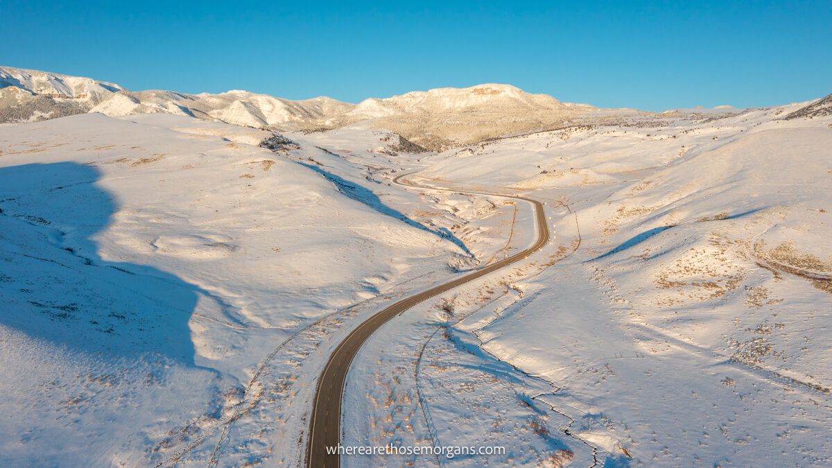 Photo of a narrow road twisting through a snowy landscape taken from above by a drone