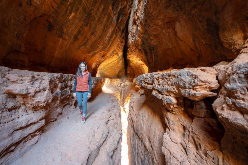 Photo of a hiker walking along a narrow ledge inside a cave with dim light sources