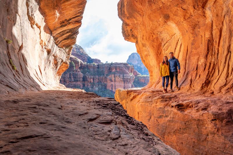 Photo of Mark and Kristen Morgan standing together inside an empty cave shaped like a subway tunnel in Sedona AZ