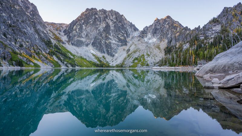 Photo of a still lake with rugged huge granite mountains reflecting