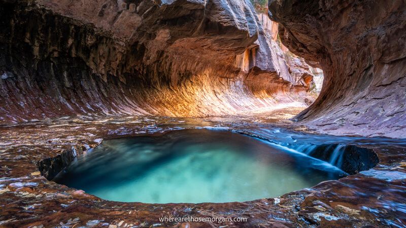 Photo of a small turquoise pool and a subway tunnel shaped rock formation filled with light