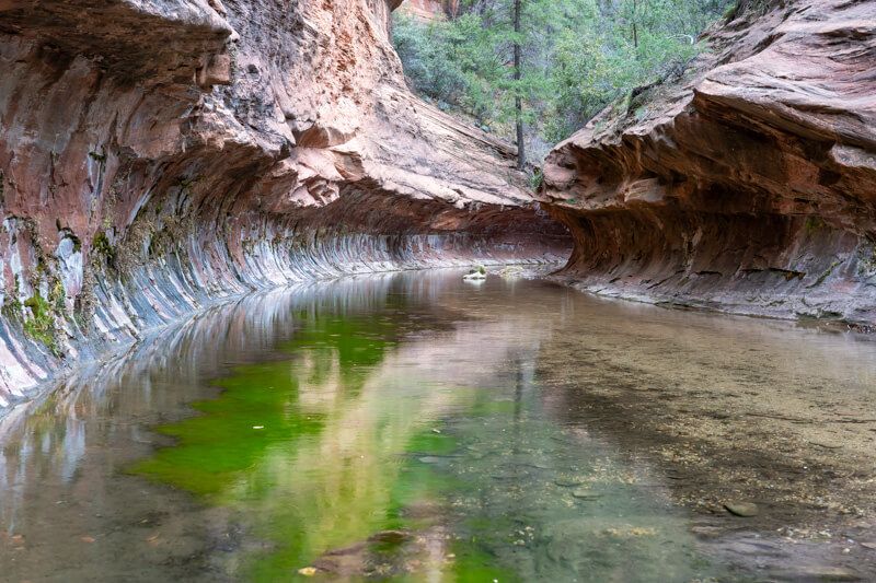 Photo of a shallow river cutting through an eroded rock formation shaped like a subway tunnel