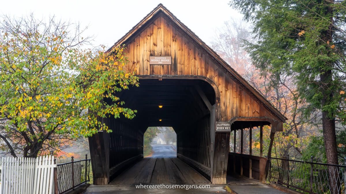 Large wooden covered bridge next to trees on a misty day