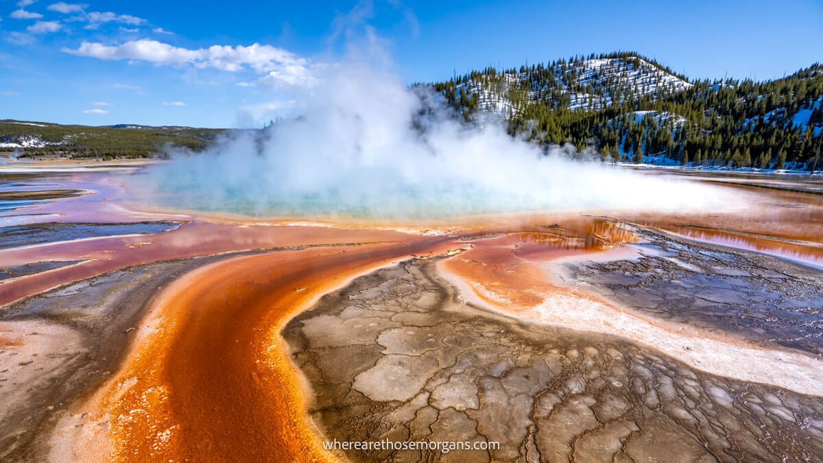 Photo of a hot spring with vibrant swirling patterns and billowing steam in Yellowstone National Park