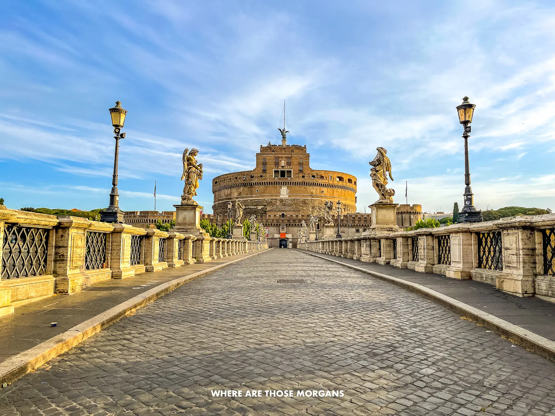 Long stone bridge path leading to the rounded Castel Sant'Angelo in Rome at dawn