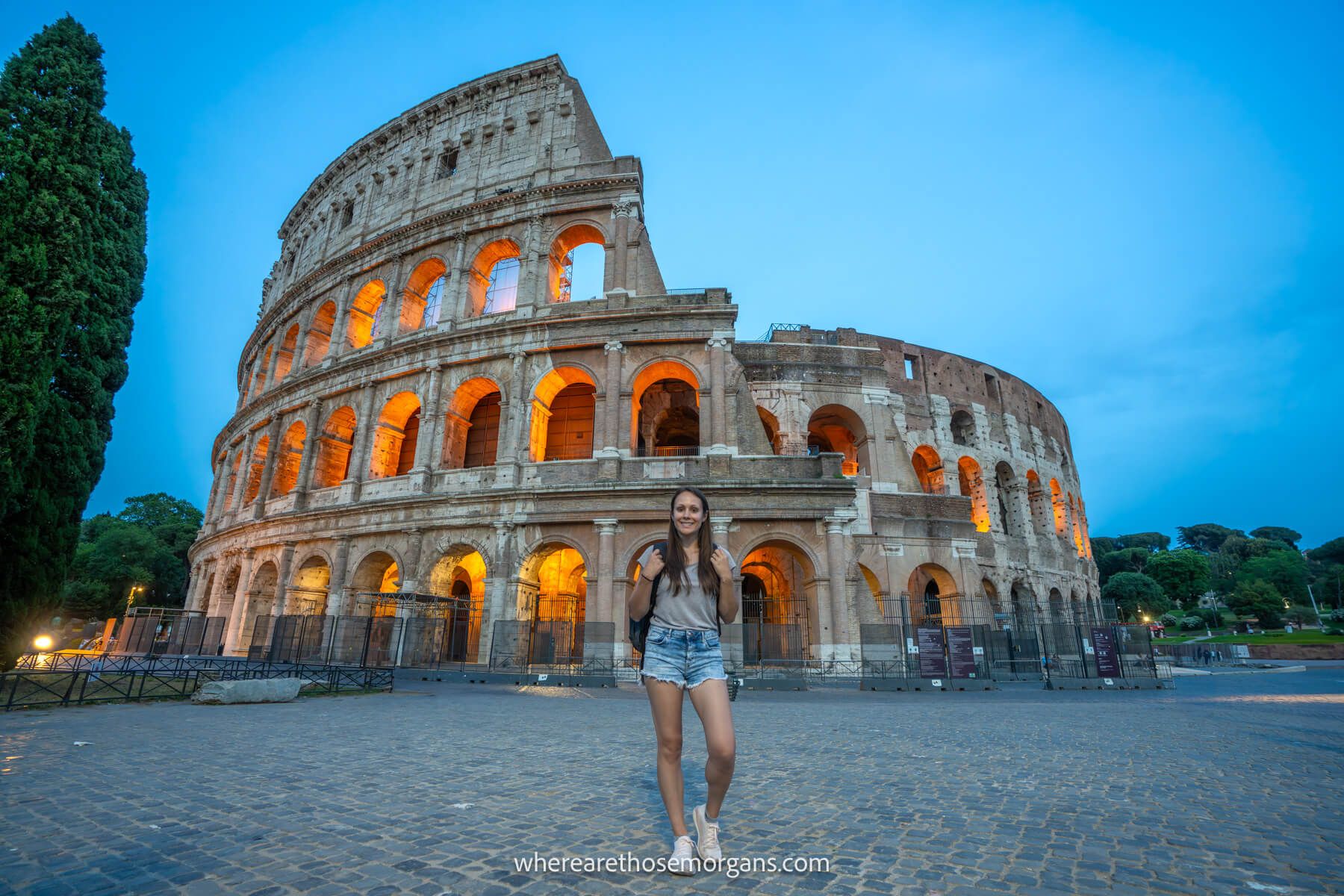 Photo of Kristen Morgan standing in front of the Colosseum lit up at night