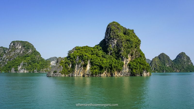 Photo of a bay with limestone karsts sticking up out of the water under a clear blue sky