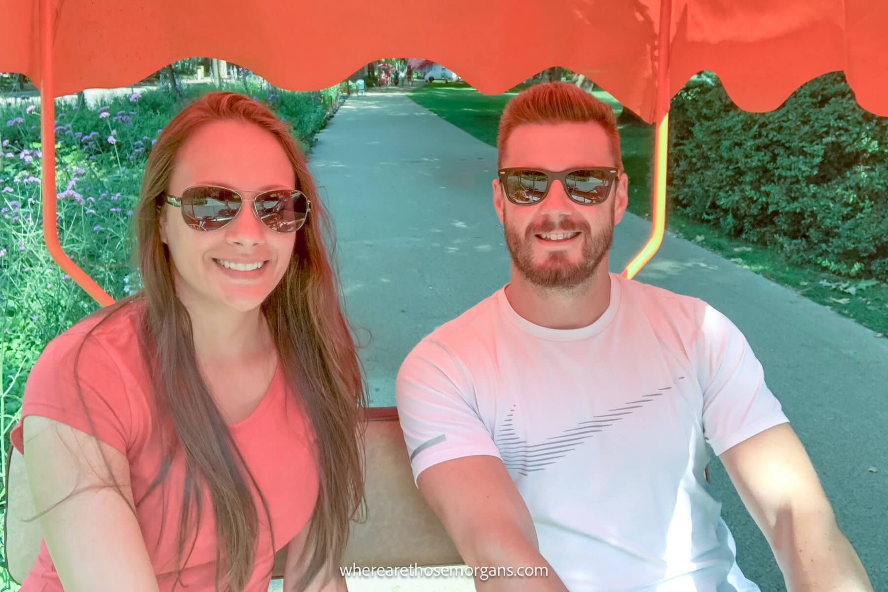 hungary where are those morgans Photo of Mark and Kristen from Where Are Those Morgans riding a four wheel bicycle with orange canopy in a park in Budapest, Hungary