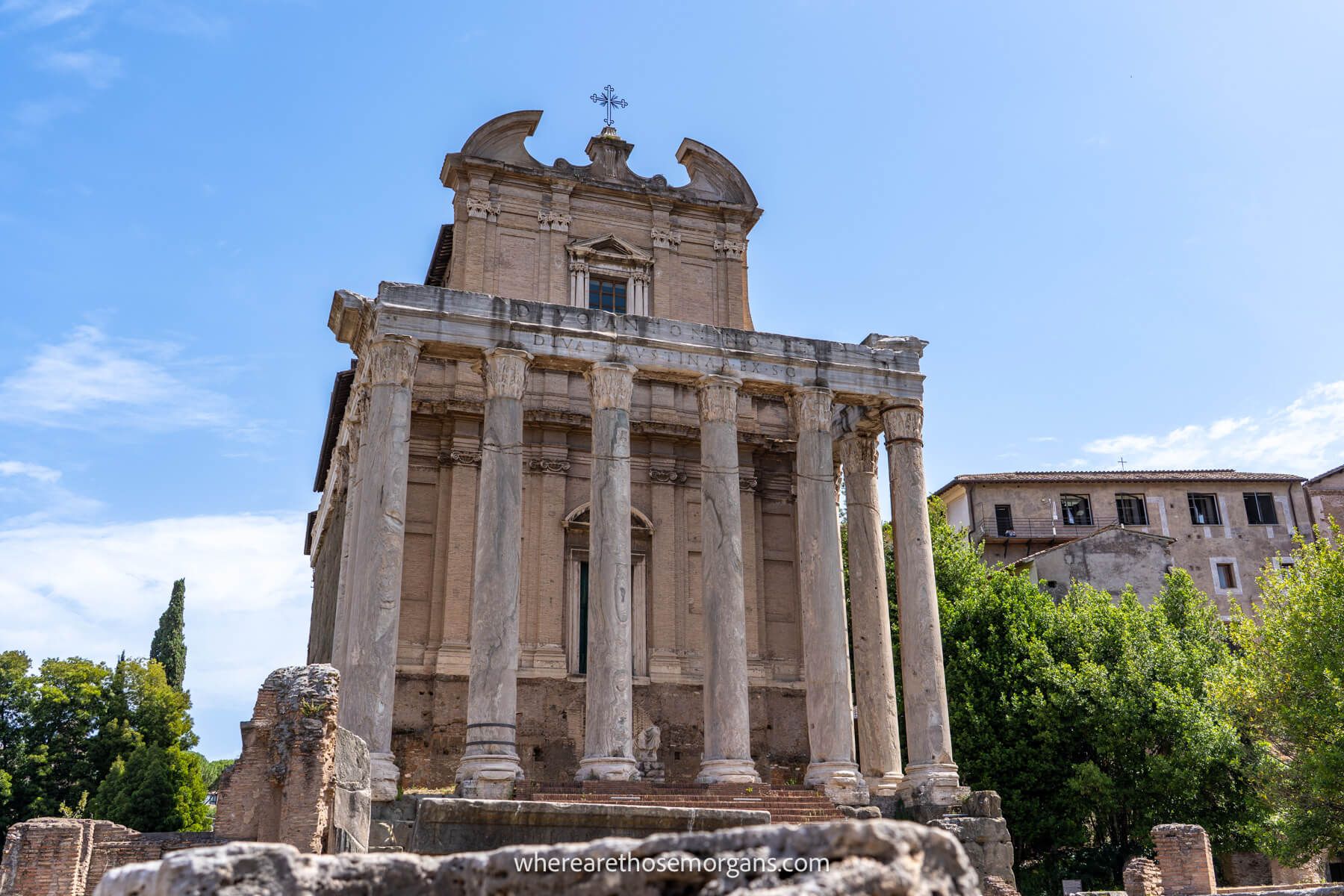 Photo of a temple ruin in the Roman Forum with trees to the side and a clear blue sky