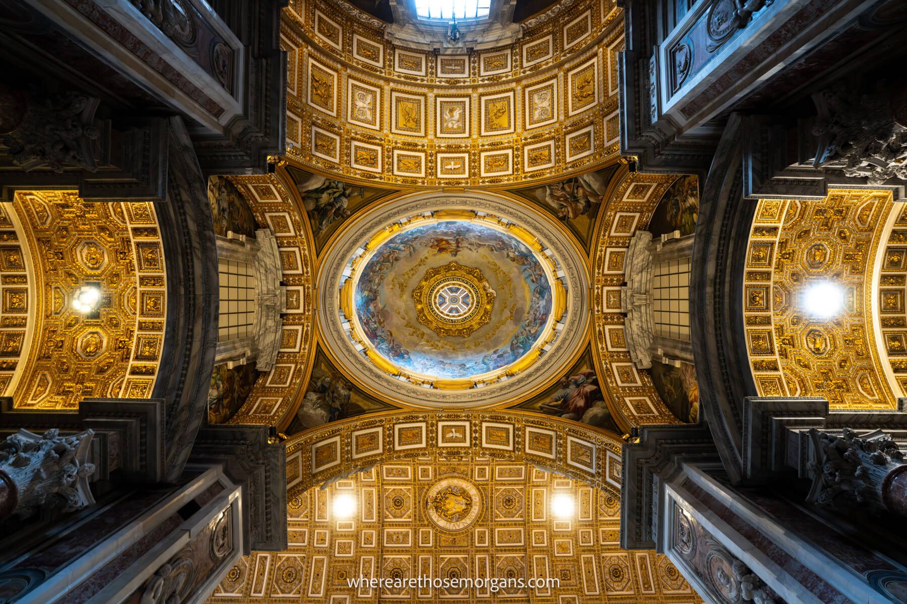 Photo of the ceiling inside St Peter's Basilica looking directly up at the patterns