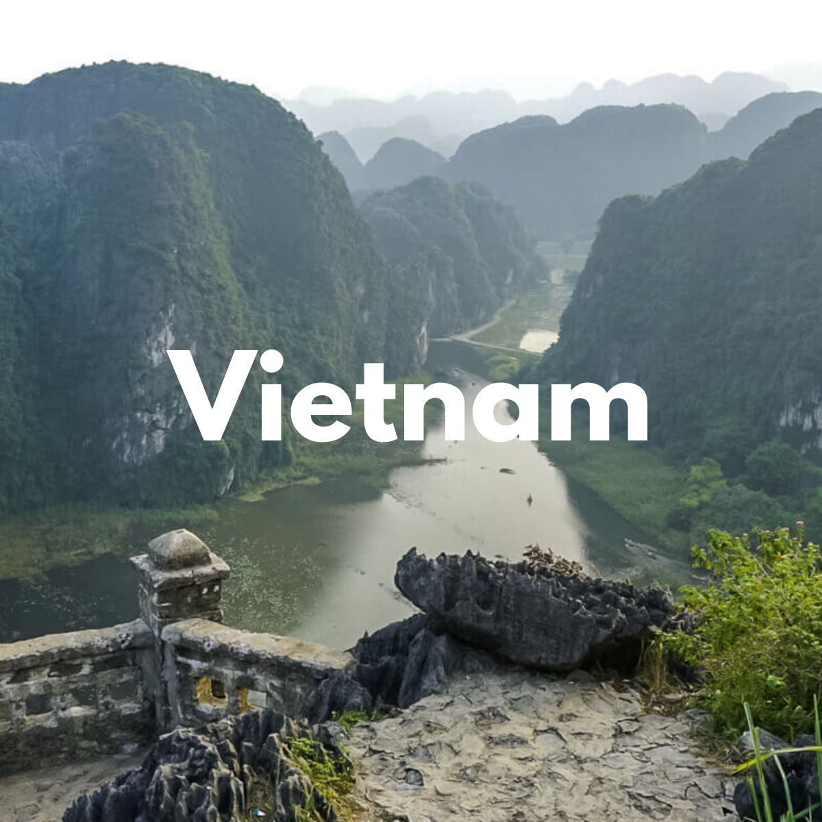 Photo of a stone staircase viewpoint overlooking a river and limestone karsts on a cloudy day with the word Vietnam overlaid