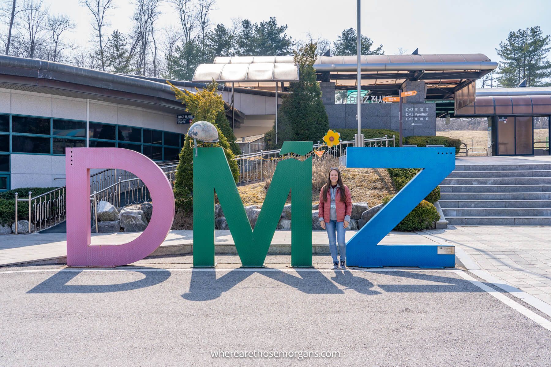 where are those morgans south korea Photo of Kristen Morgan from Where Are Those Morgans standing in between tall letters reading DMZ on a sunny day in South Korea