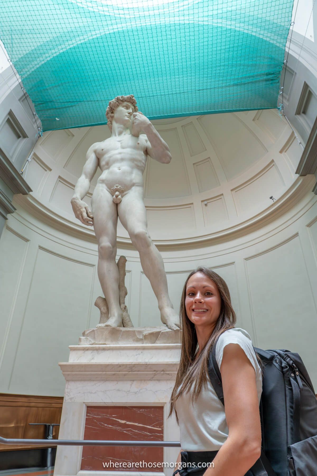 Photo of Kristen Morgan from Where Are Those Morgans standing below and next to the statue of David in the Accademia Gallery