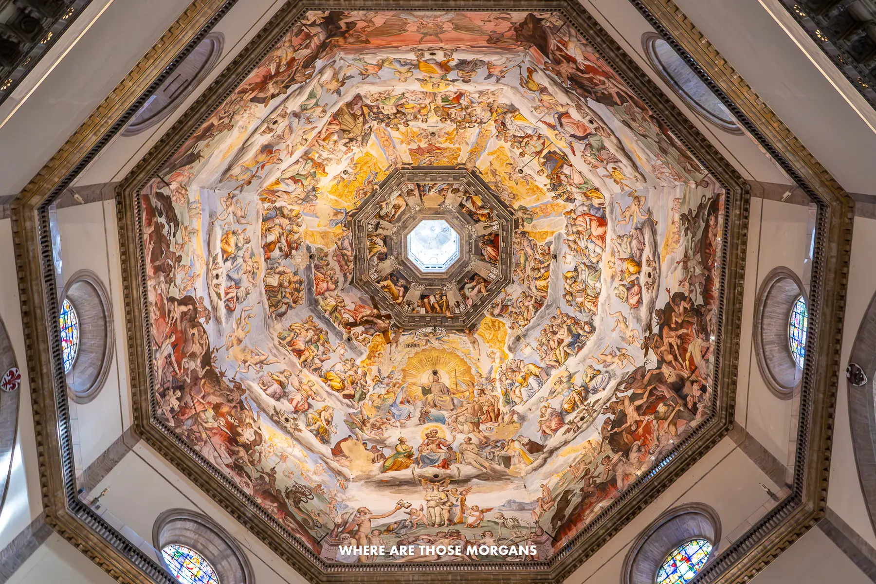 Looking up at a ceiling painting covering the underneath of a dome inside Florence Cathedral