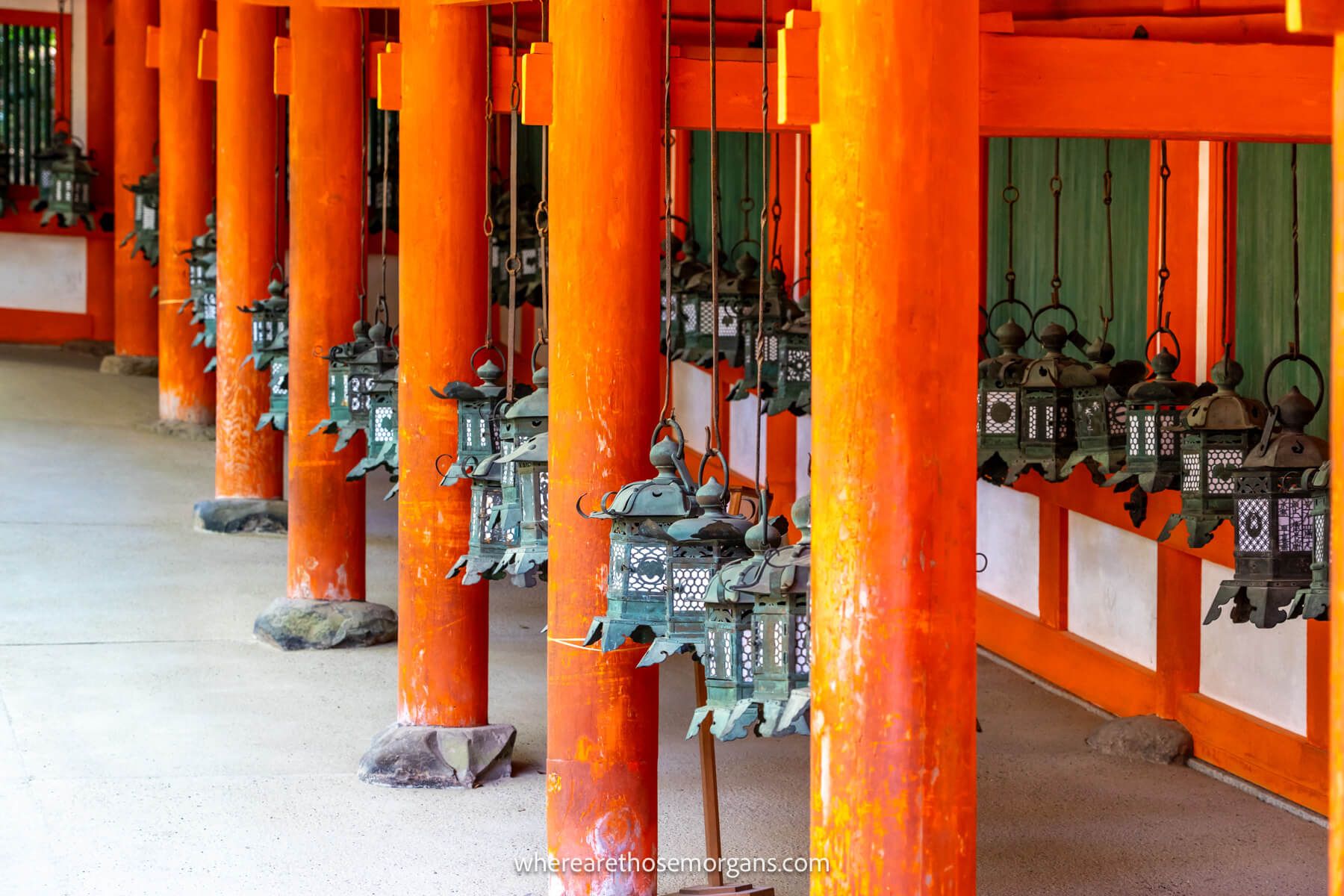 Photo of lanterns hanging from orange colored wooden frames at a shrine in Japan