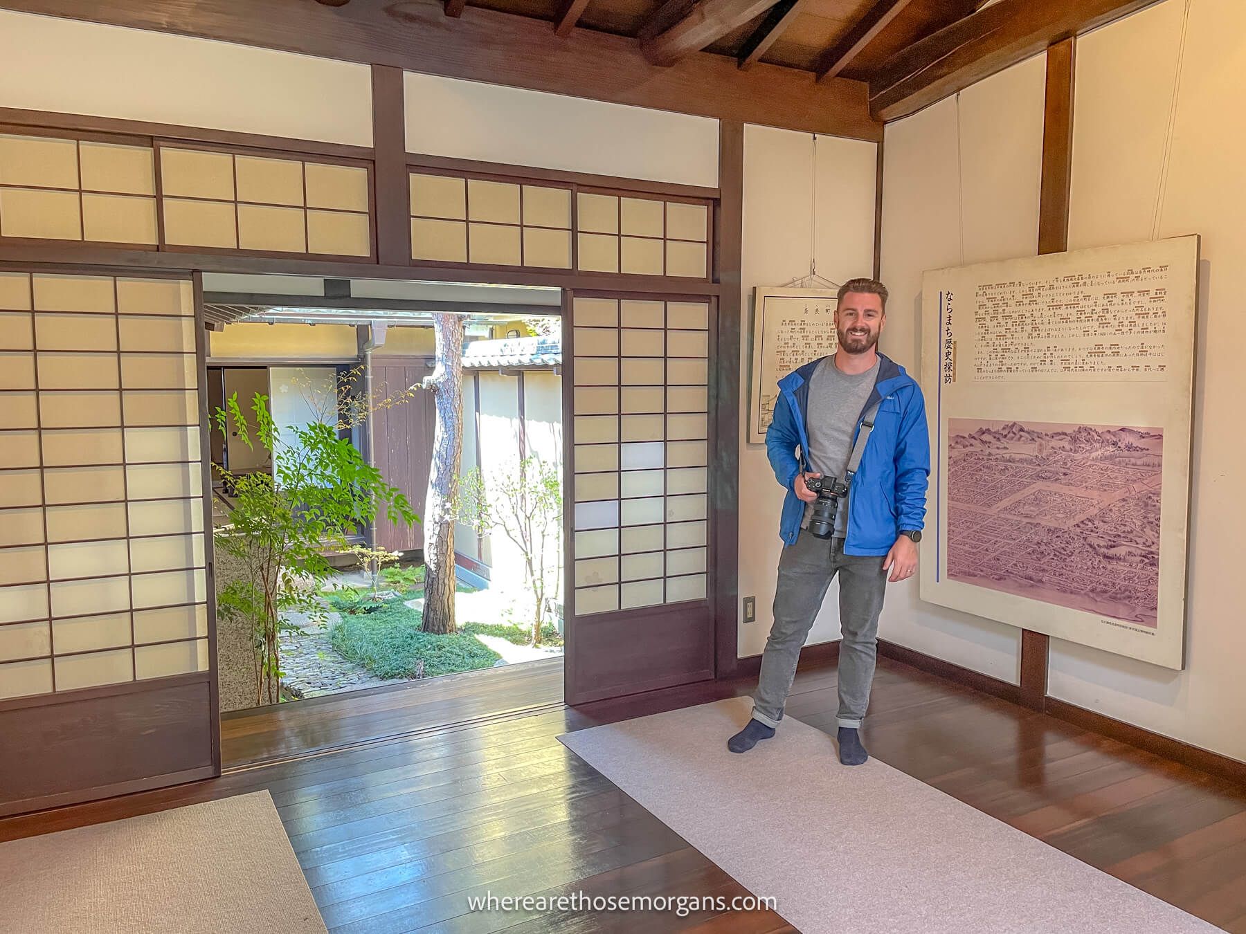 Photo of a tourist standing inside a traditional Japanese house holding a camera