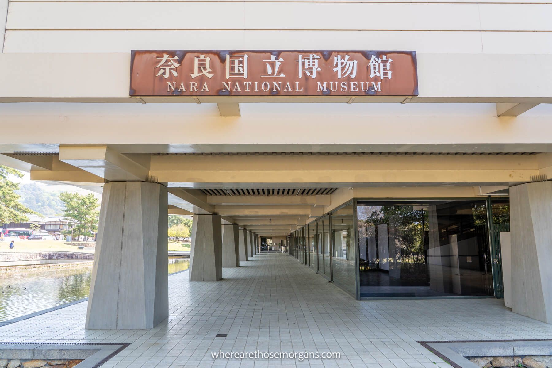Photo of a concrete building with a tunnel like entrance next to pillars supporting the structure with the words Nara National Museum