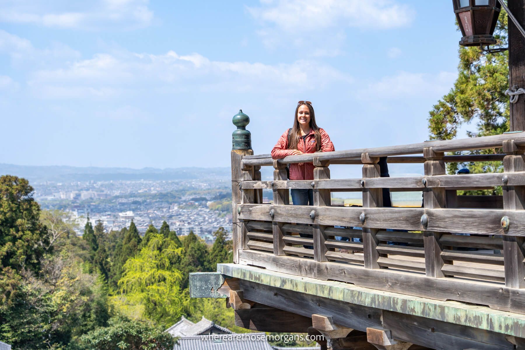 Photo of Kristen Morgan standing in the corner of an elevated balcony with views over Nara behind on a sunny day