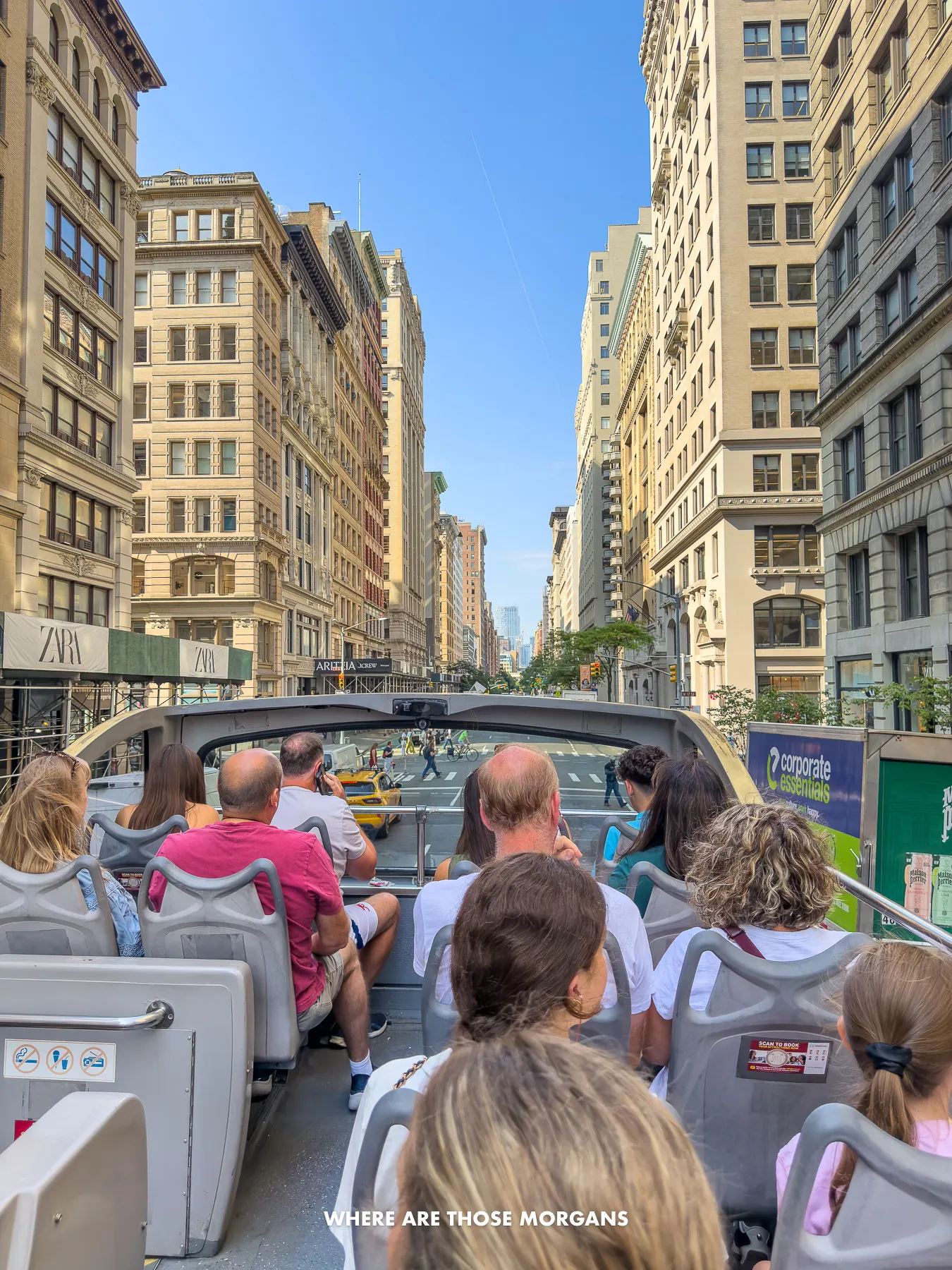 Photo of people sat on the top deck of a Big Bus looking at views of skyscrapers