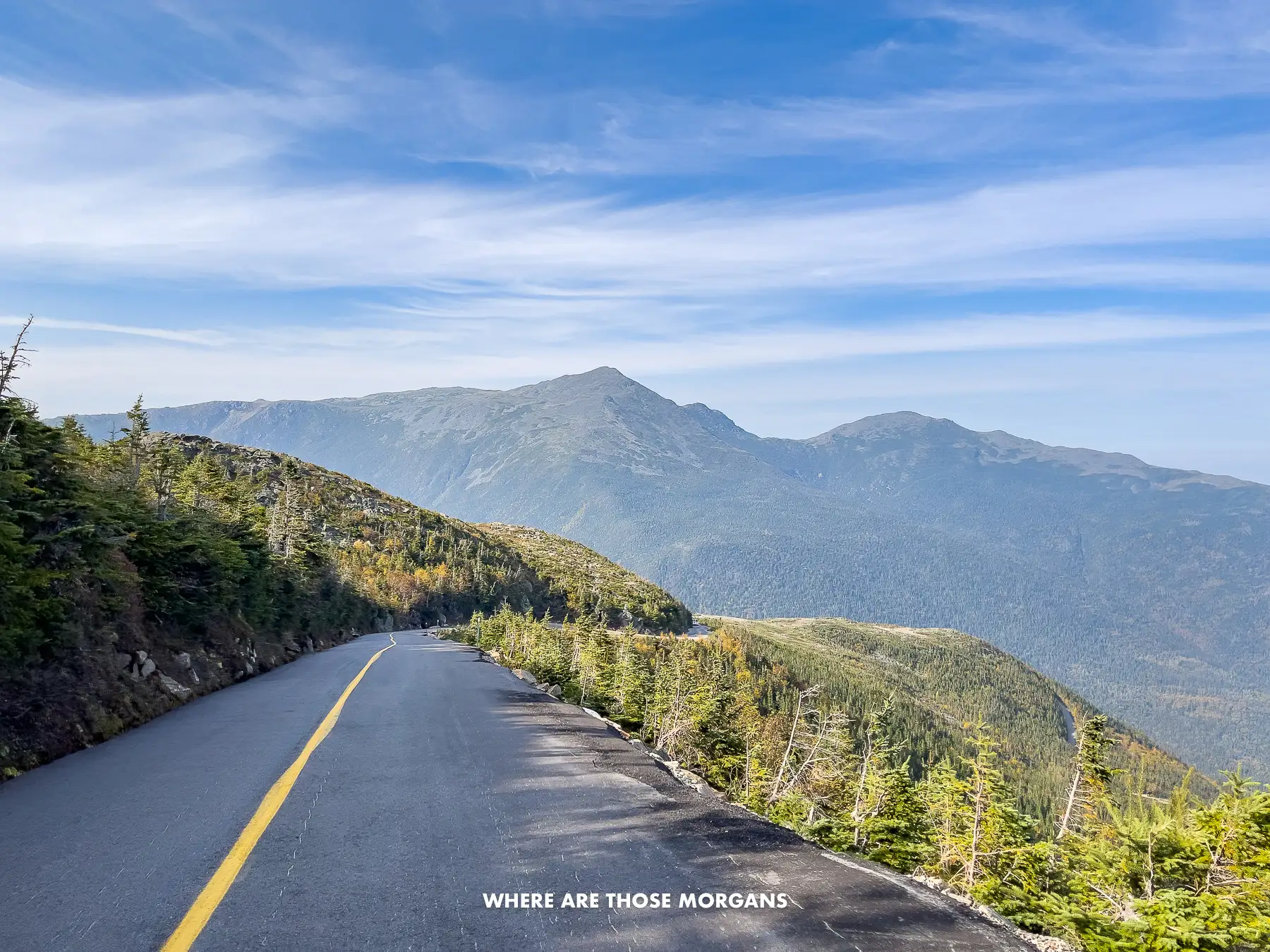 Photo of a road on the edge of a mountain with distant views over another mountain in NH