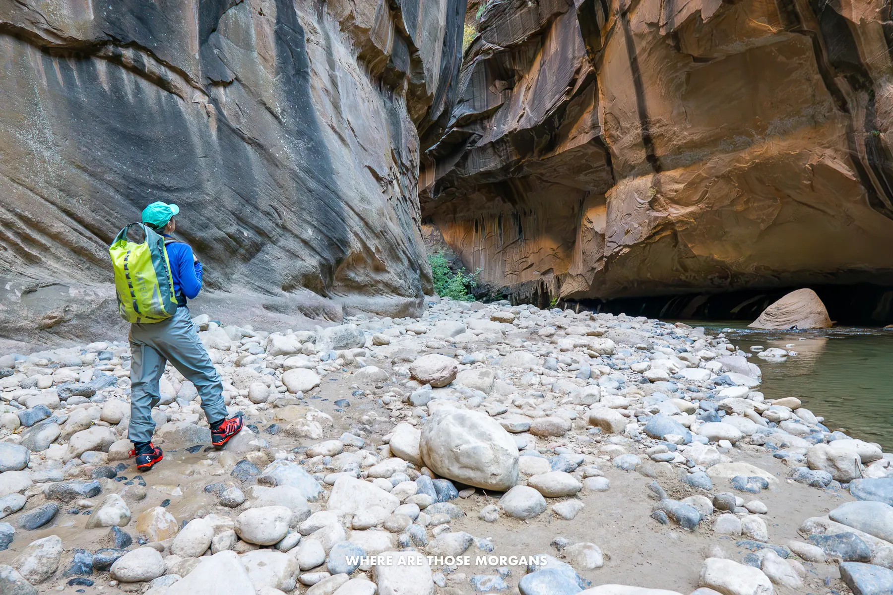 Photo of Kristen in waterproof gear inside The Narrows walking on rocks in a slot canyon