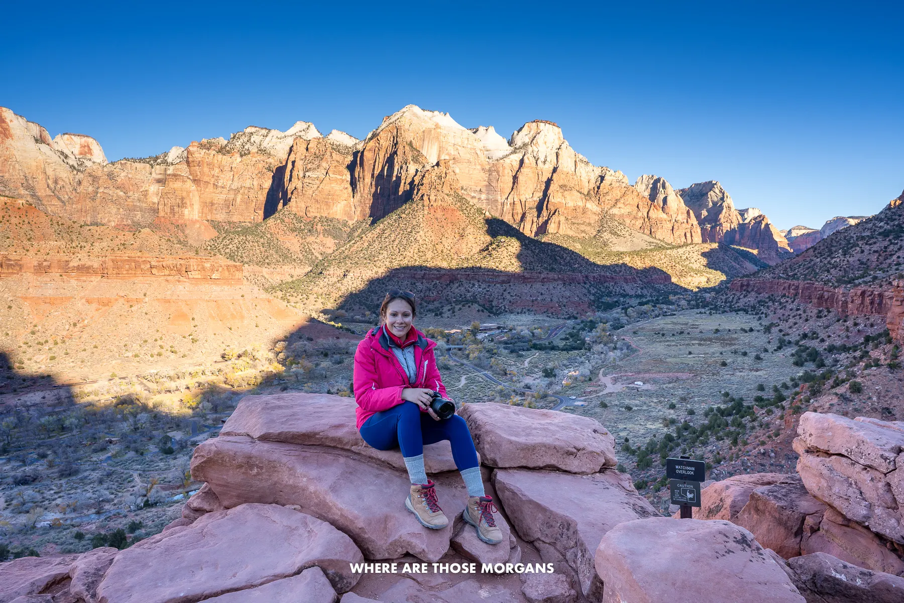 Photo of Kristen sat on red rocks at Watchman Trail Overlook at sunrise in the main Zion canyon