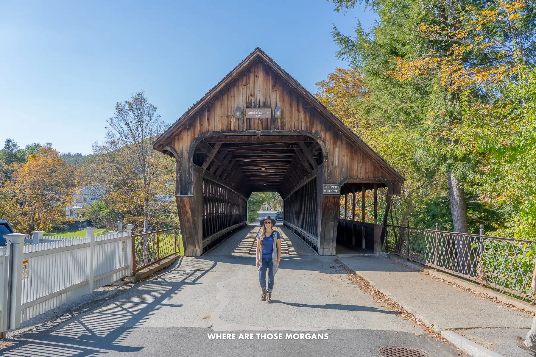 Photo of a tourist standing in front of Woodstock Middle Covered Bridge on a sunny day
