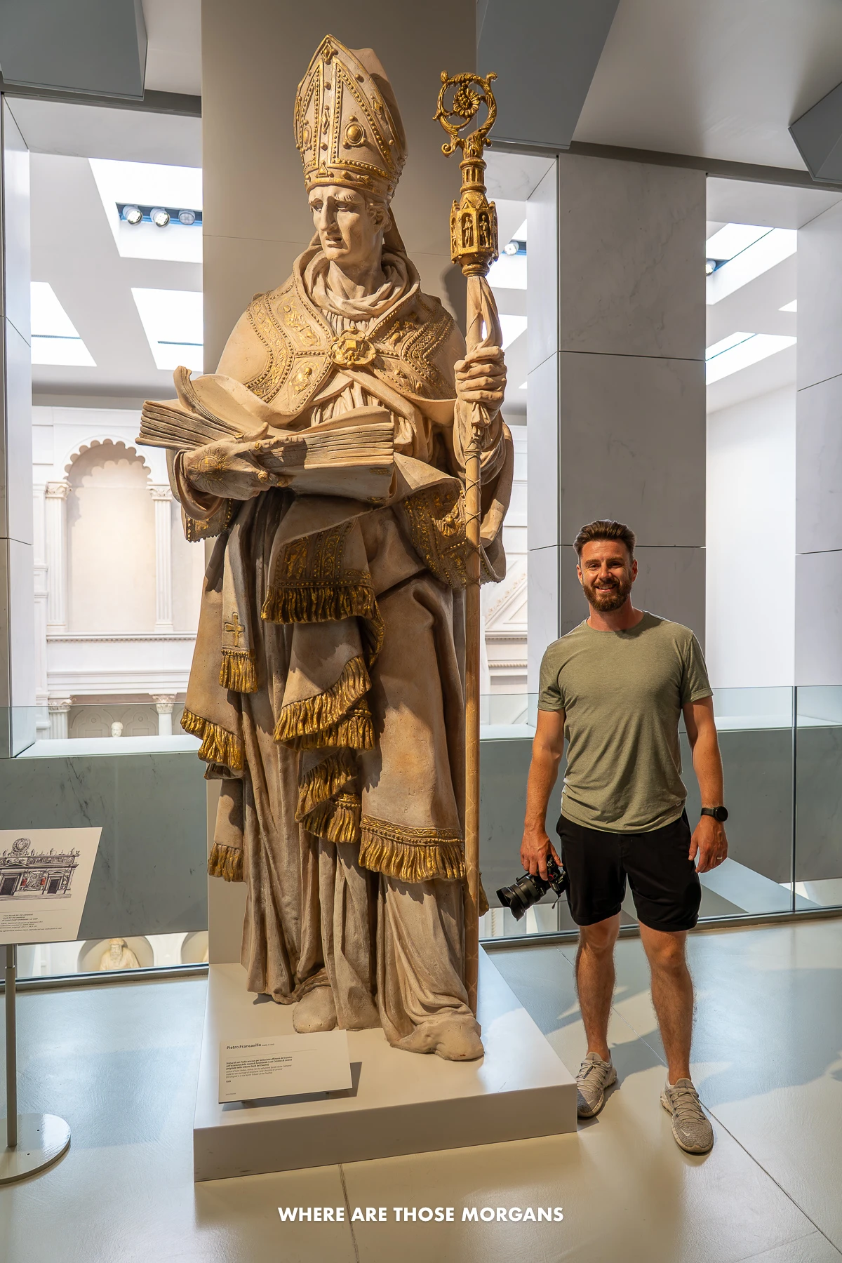 Photo of a tourist standing next to s sculpture in a museum in Italy