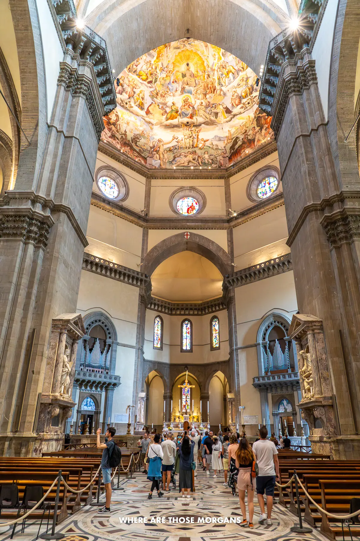 Photo of the inside of Florence Cathedral with tourists walking and looking up at the dome