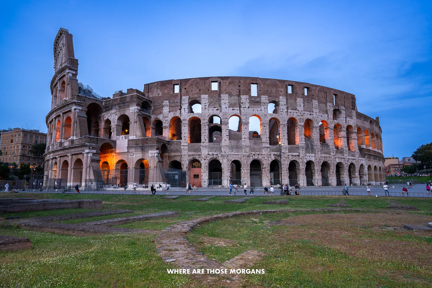 The Colosseum with orange lights in the windows at dusk with a blue sky
