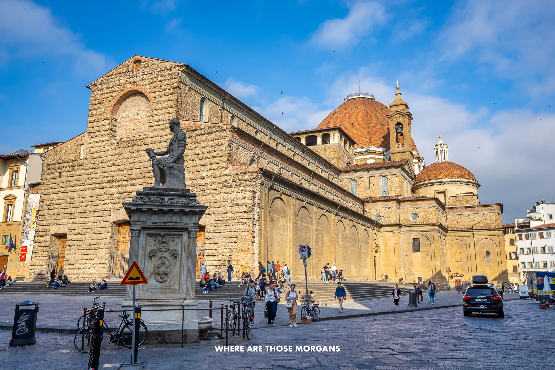 Photo of the Basilica di San Lorenzo glowing under sunlight with people walking in the shadowed streets below