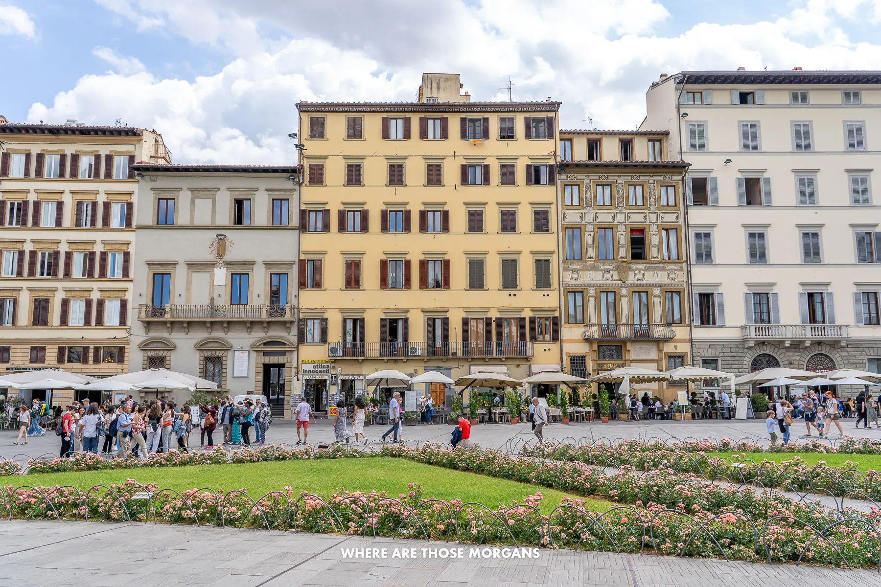 Photo of a row of colorful 5 story buildings with tourists eating and drinking in cafes or restaurants on the ground floor