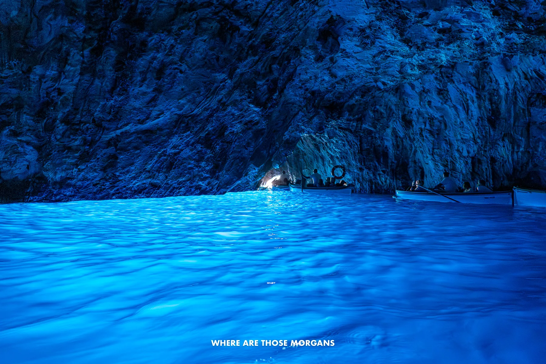 Photo of bright blue colored water glowing and reflecting all around the Blue Grotto sea cave in Capri