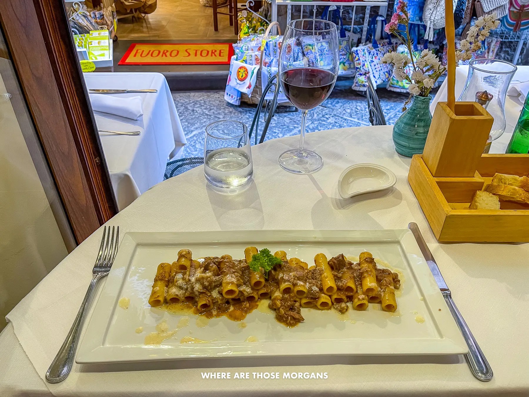 Photo of a rectangular white plate with cannelloni di sorrentina on a table opening out onto a street