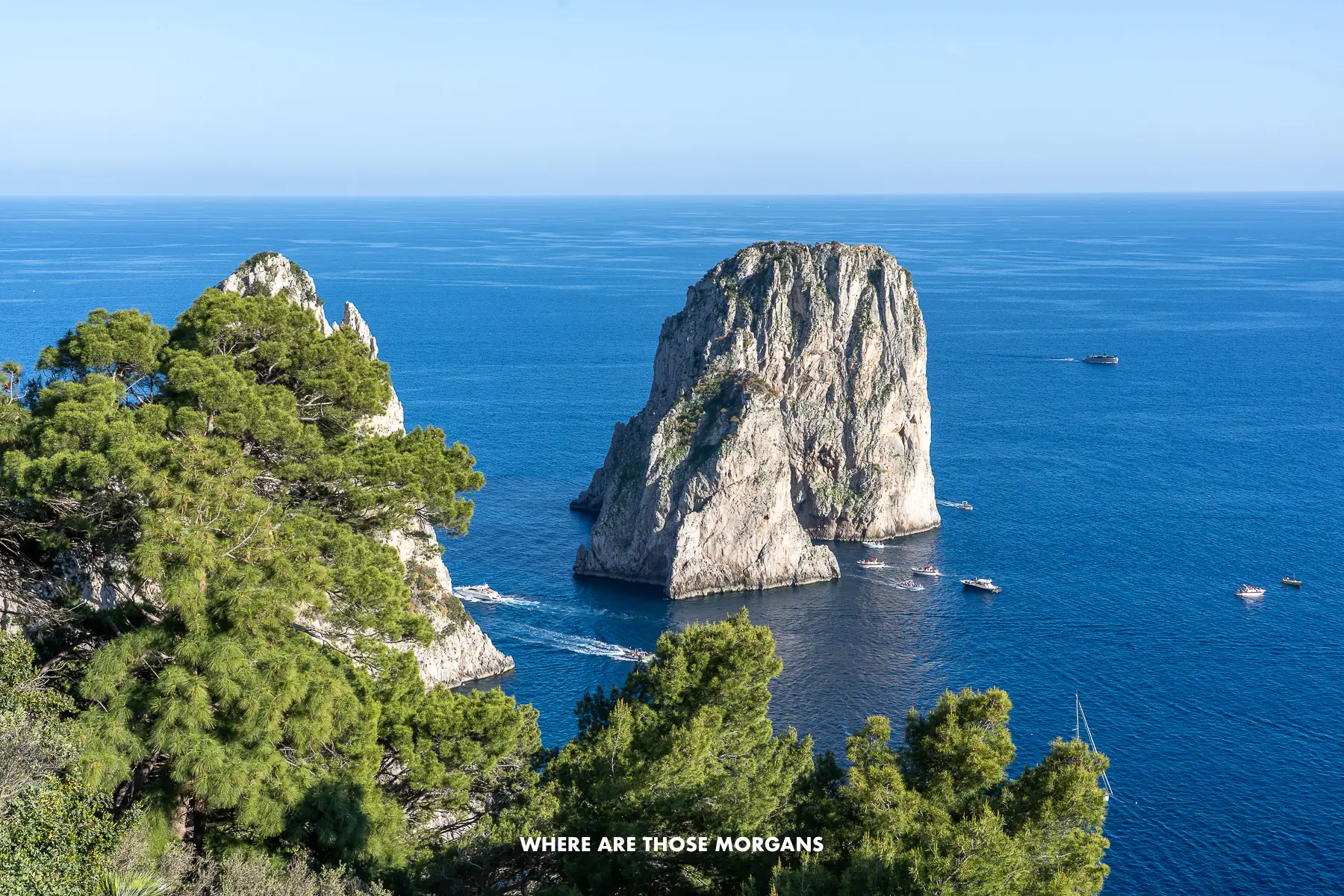 Photo of the Faraglioni rock formations at sea on the coastline of Capri on a sunny day