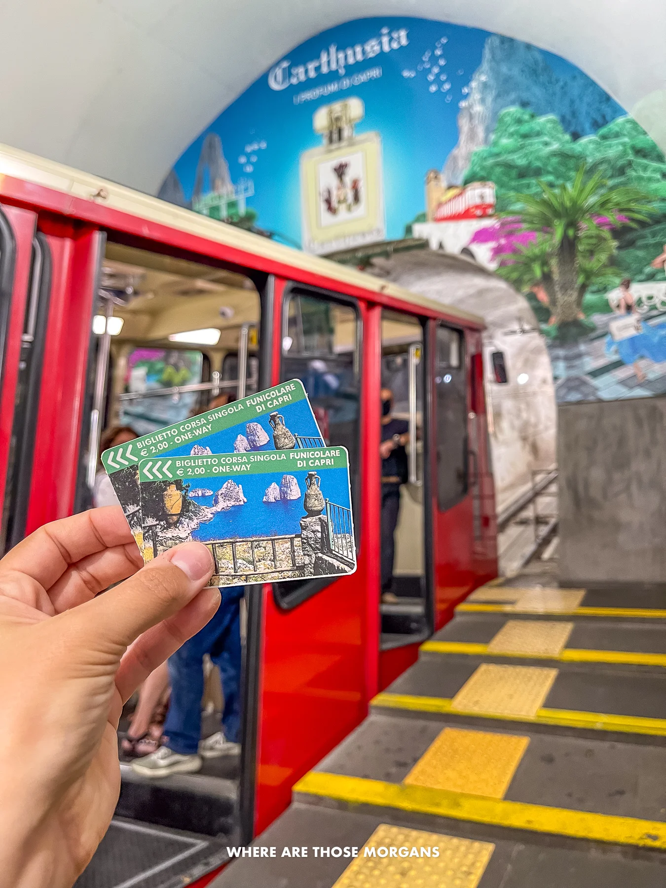Photo of a hand holding two tickets for a funicular ride in front of the carriage