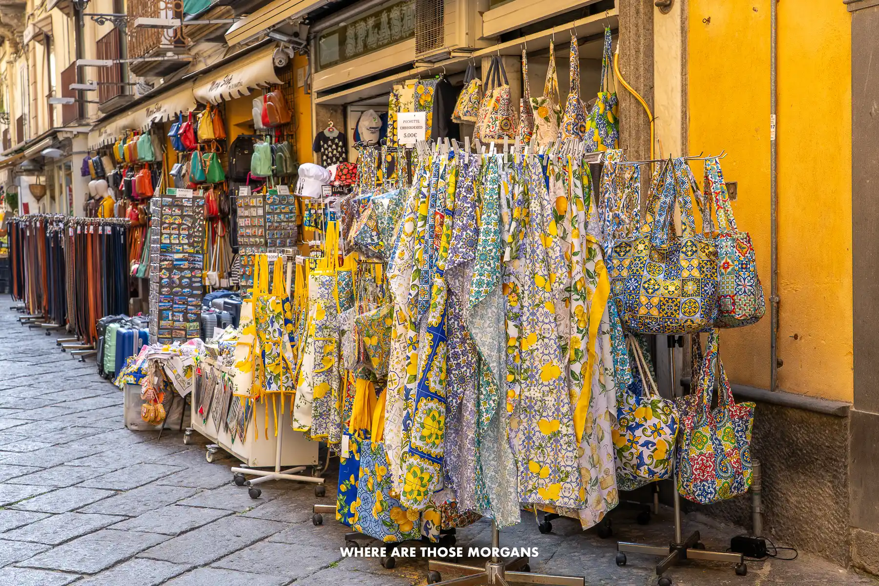 Photo of clothes with lemon designs hanging on a rack on a cobbled street in Italy