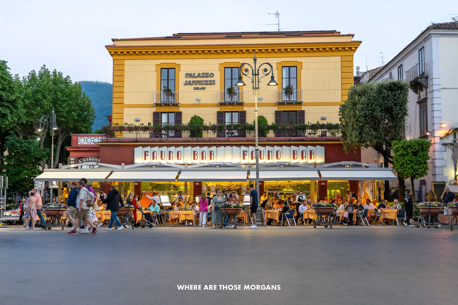 Photo of a restaurant and bar with lots of tourists eating and drinking under a canopy in Italy