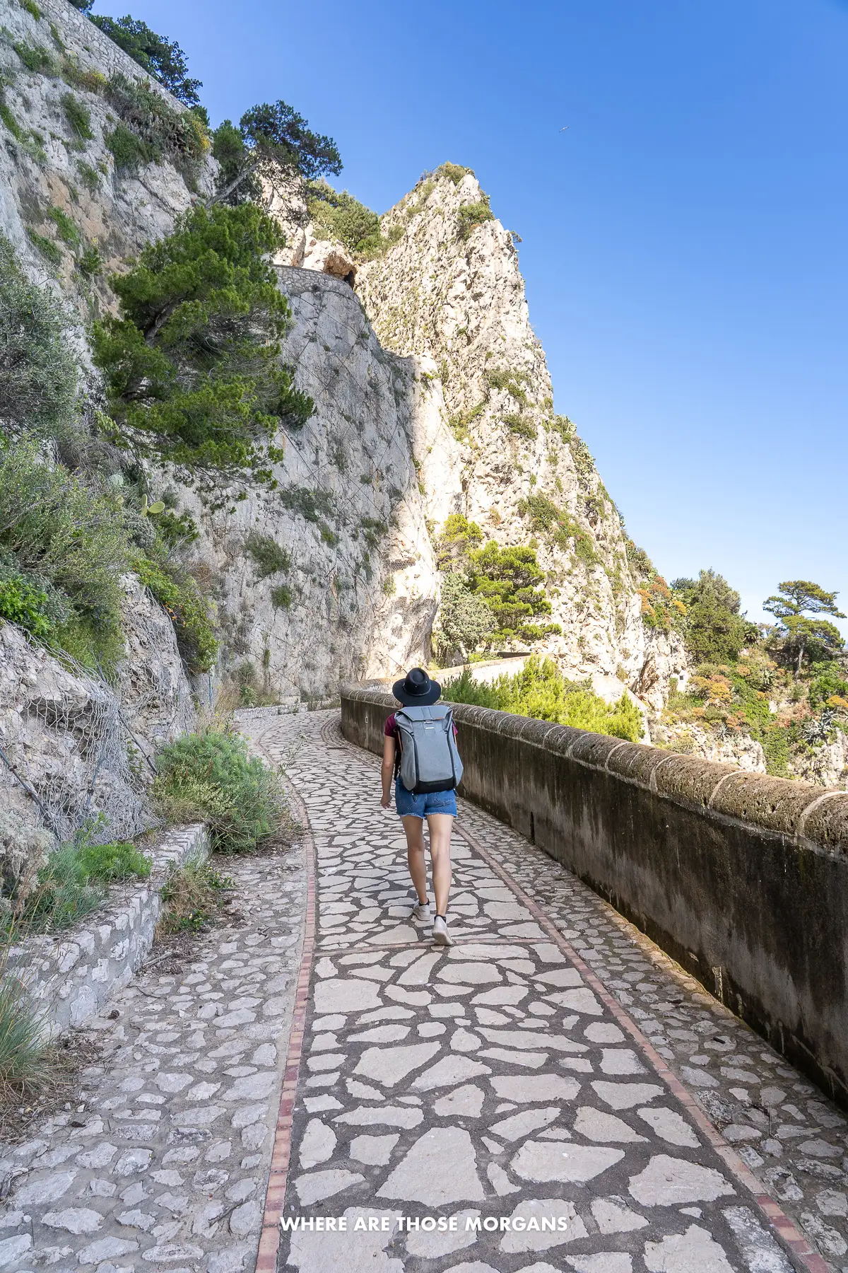 Photo of a tourist walking up a narrow cliffside path in Italy