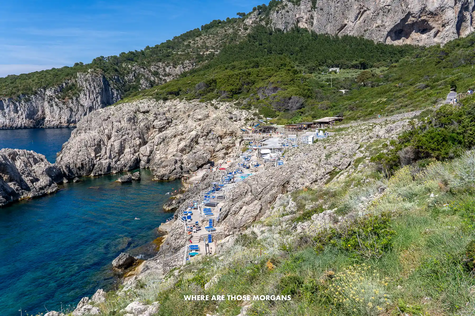 Photo of a headland and cove with sun loungers out on the rocks next to the sea in Italy