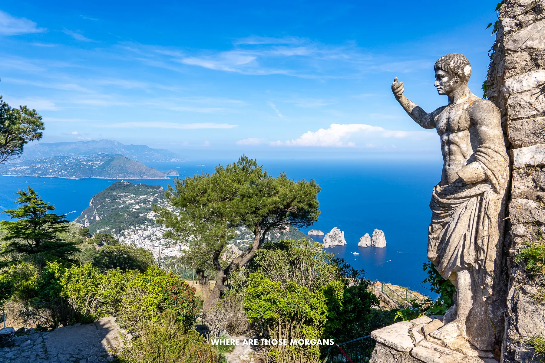 Photo of the view over Capri from the top of Monte Solaro next to a small statue of the Emperor Augustus on a clear day