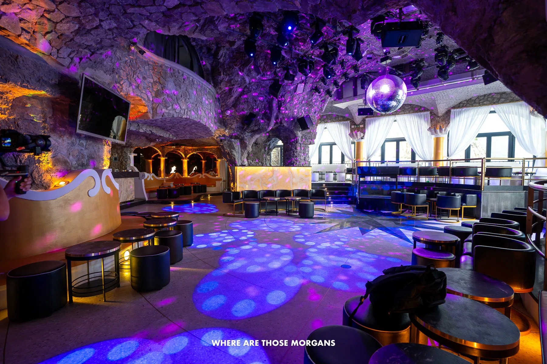 Photo of the inside of a nightclub that looks like a cave with purple lights and bar areas