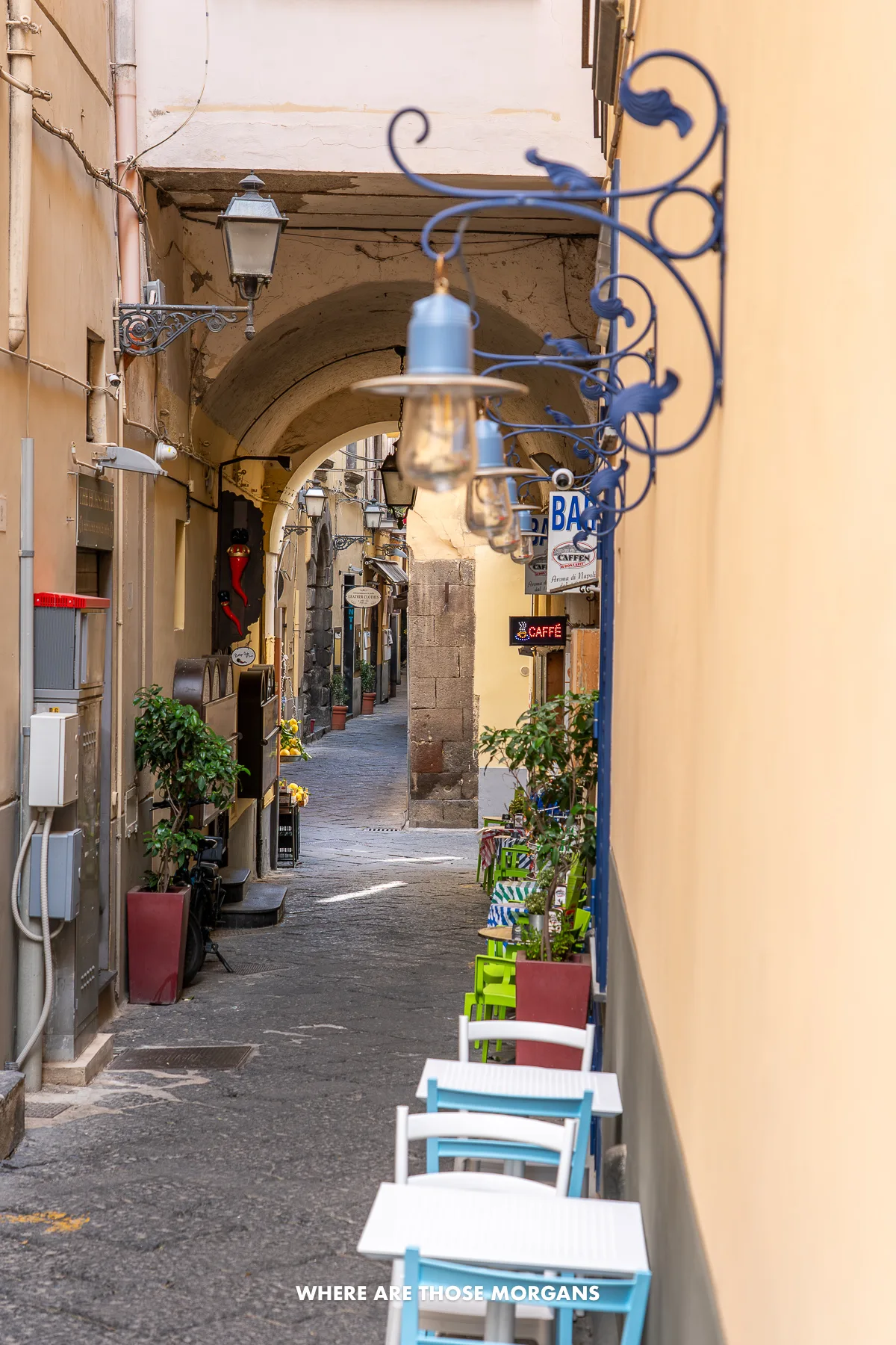 Photo of a narrow cobbled alley with small tables and chairs to one side in the Amalfi Coast