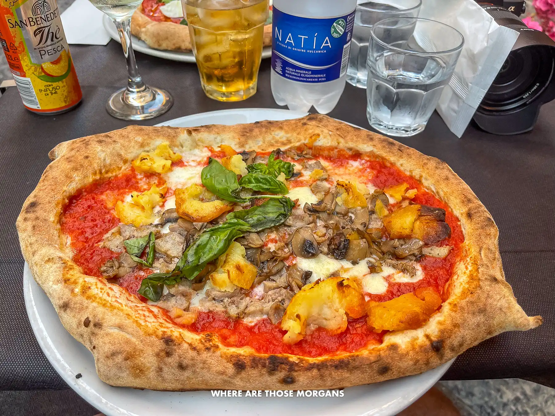 Photo of a pizza topped with potatoes, basil and mushrooms in Italy
