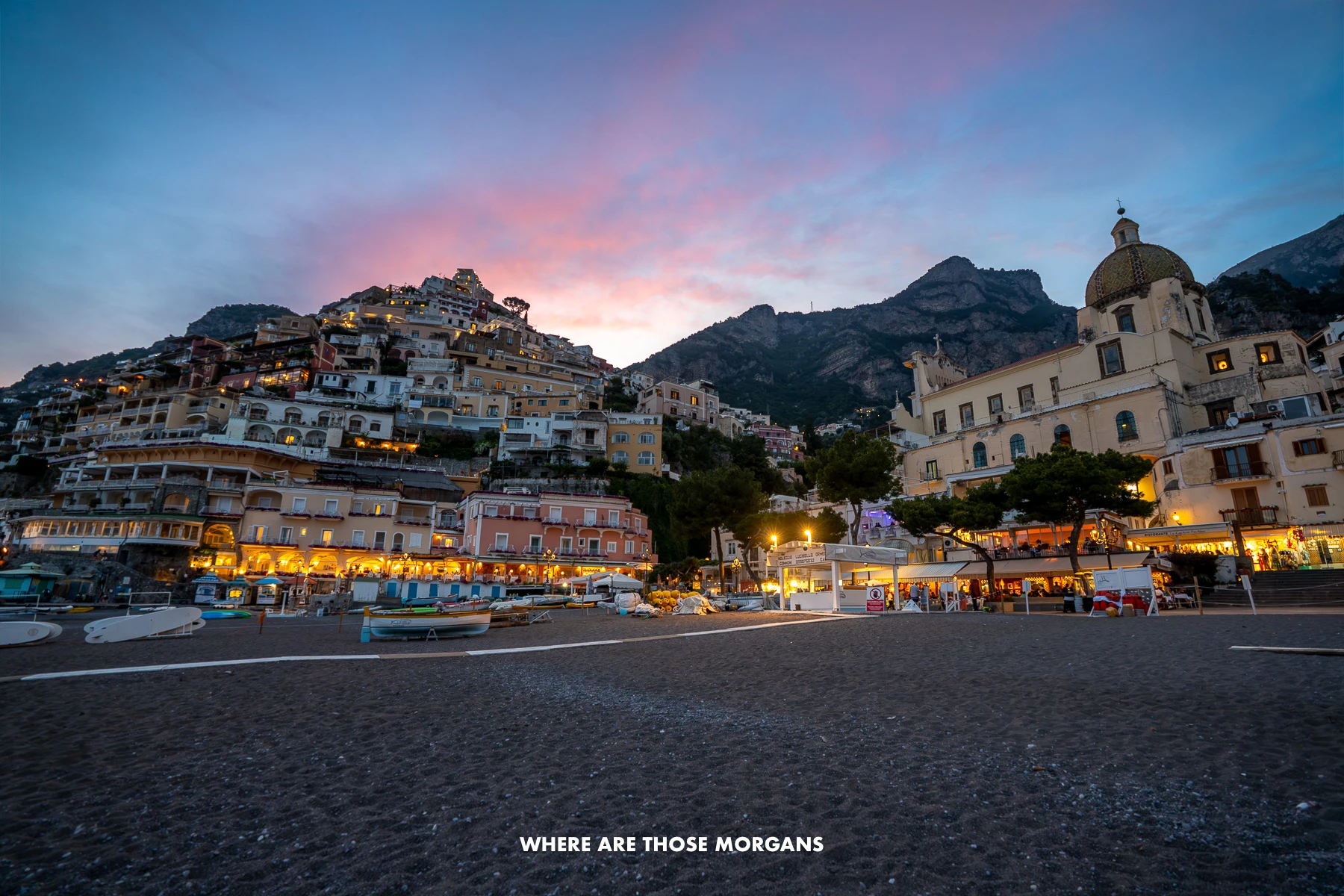 Photo of Positano at sunset from the beach looking up at the town and colorful clouds